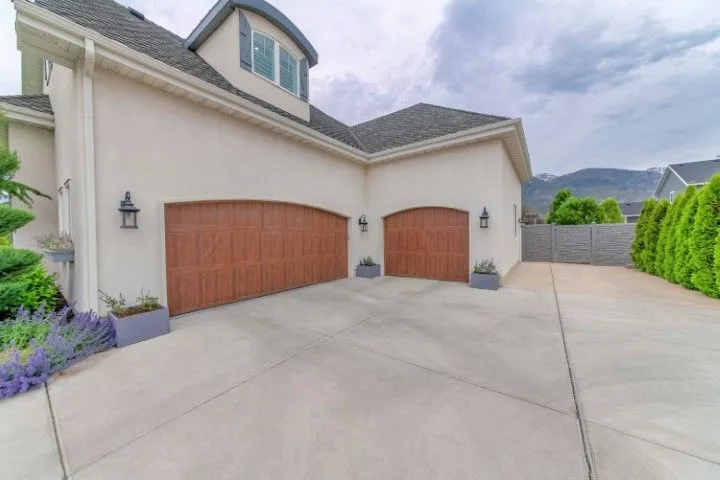 Modern suburban home exterior with two wooden garage doors and a wide concrete driveway