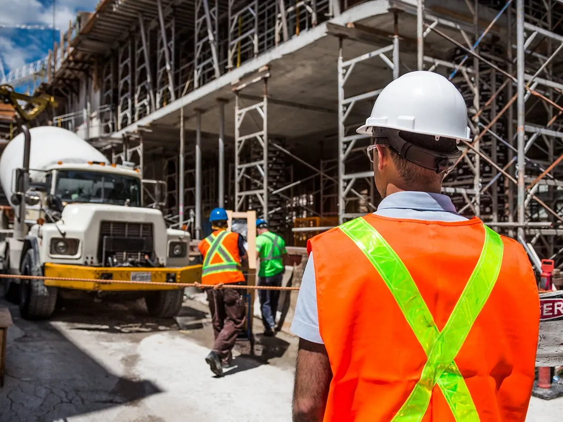 Ready-mix concrete truck and a worker in a safety vest at a construction site, Bartlesville